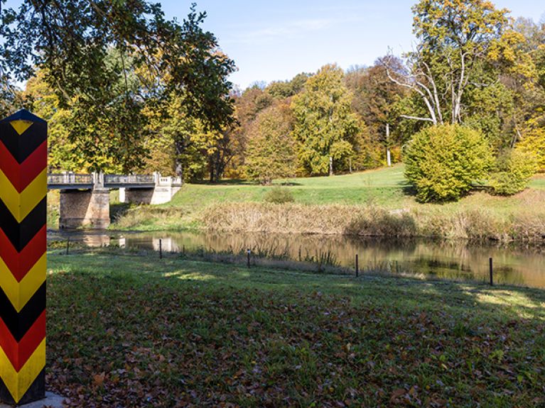 Dezent markieren Grenzpfähle die Staatsgrenze mitten im Park.