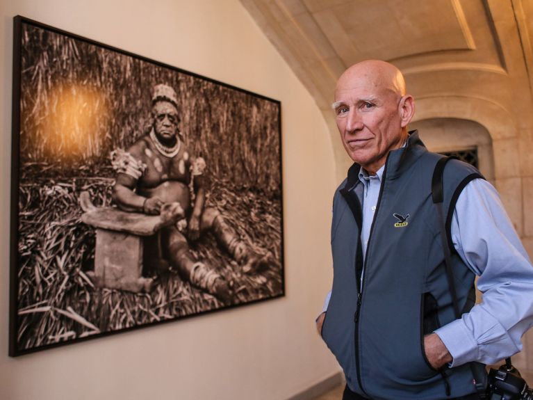 Sebastião Salgado ao lado de uma fotografia da sua série “Gênesis” 